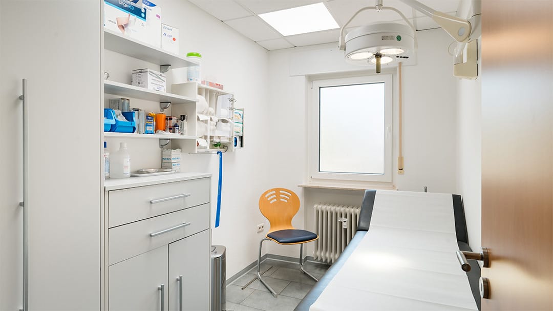 Ein Behandlungsraum mit einer Liege, OP-Leuchte und Medizinschrank